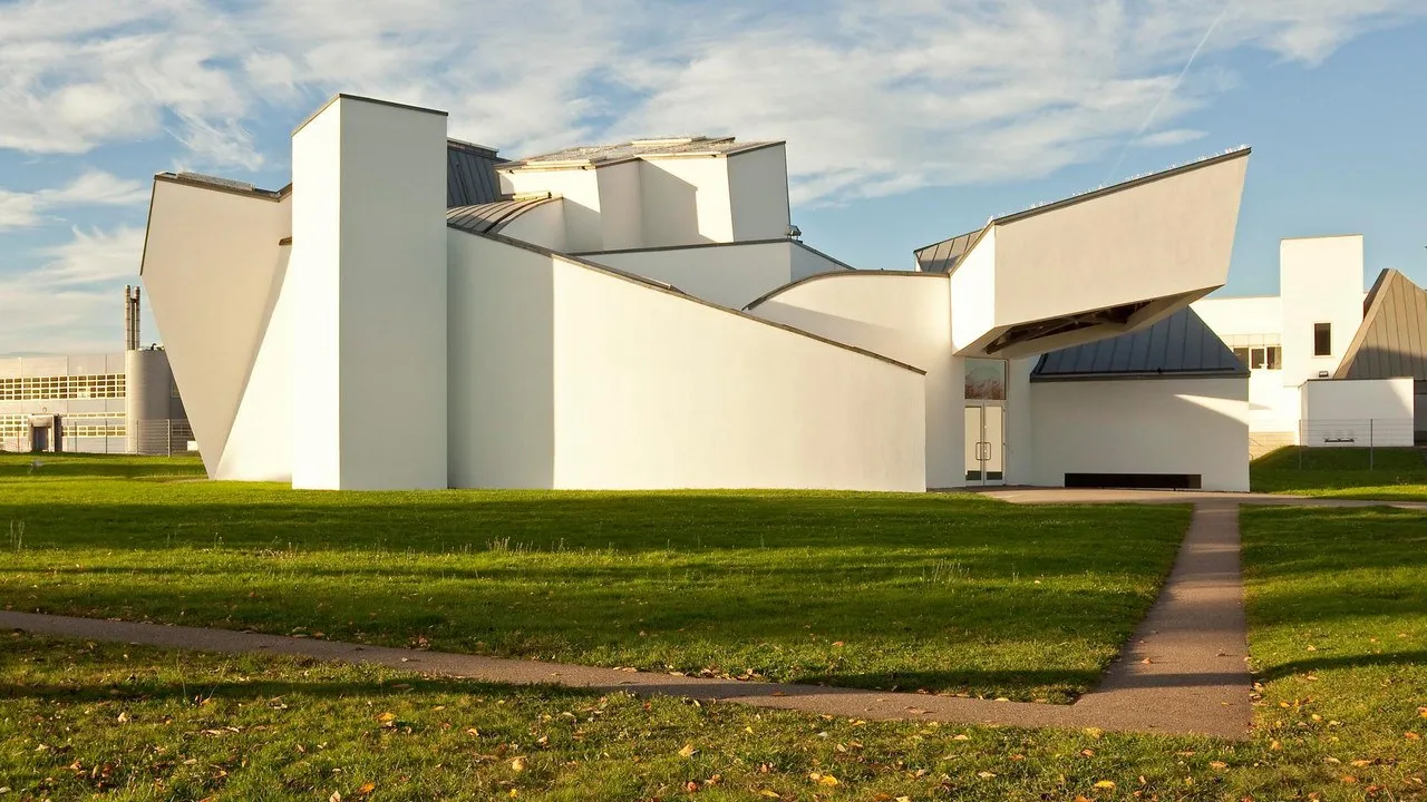 Fachada blanca de formas angulosas del Vitra Design Museum, de Frank Gehry, sobre un césped verde