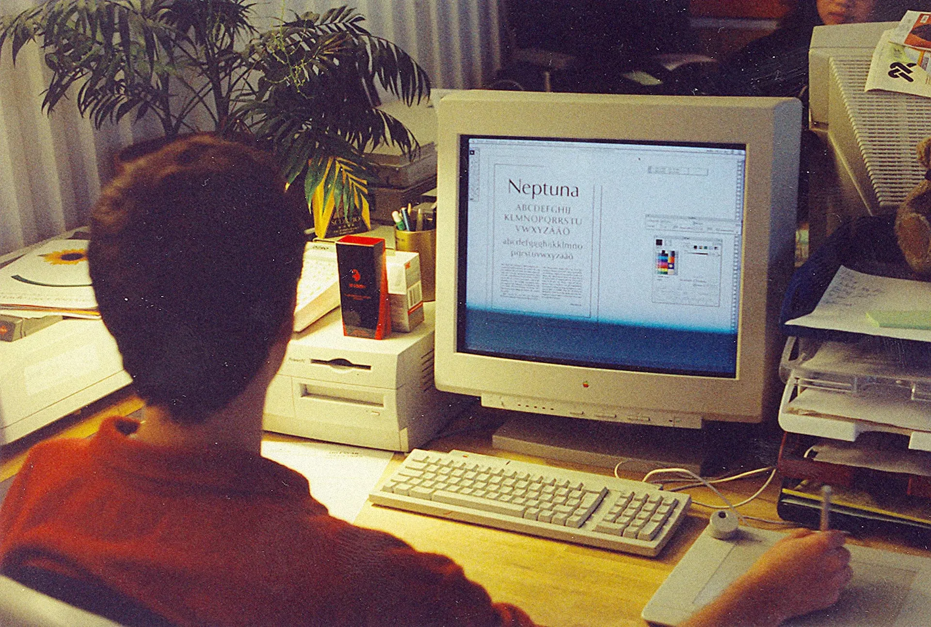 Fotografía de los años noventa de un joven frente a un ordenador Apple con la palabra Neptuna en la pantalla