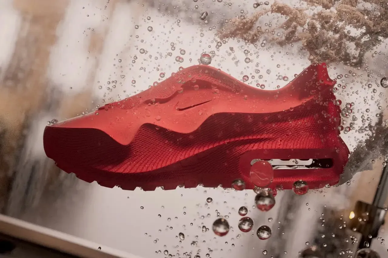 Air Max 1000 roja suspendida en el agua entre burbujas, con la textura en relieve de su superficie y la cámara de aire del talón visible