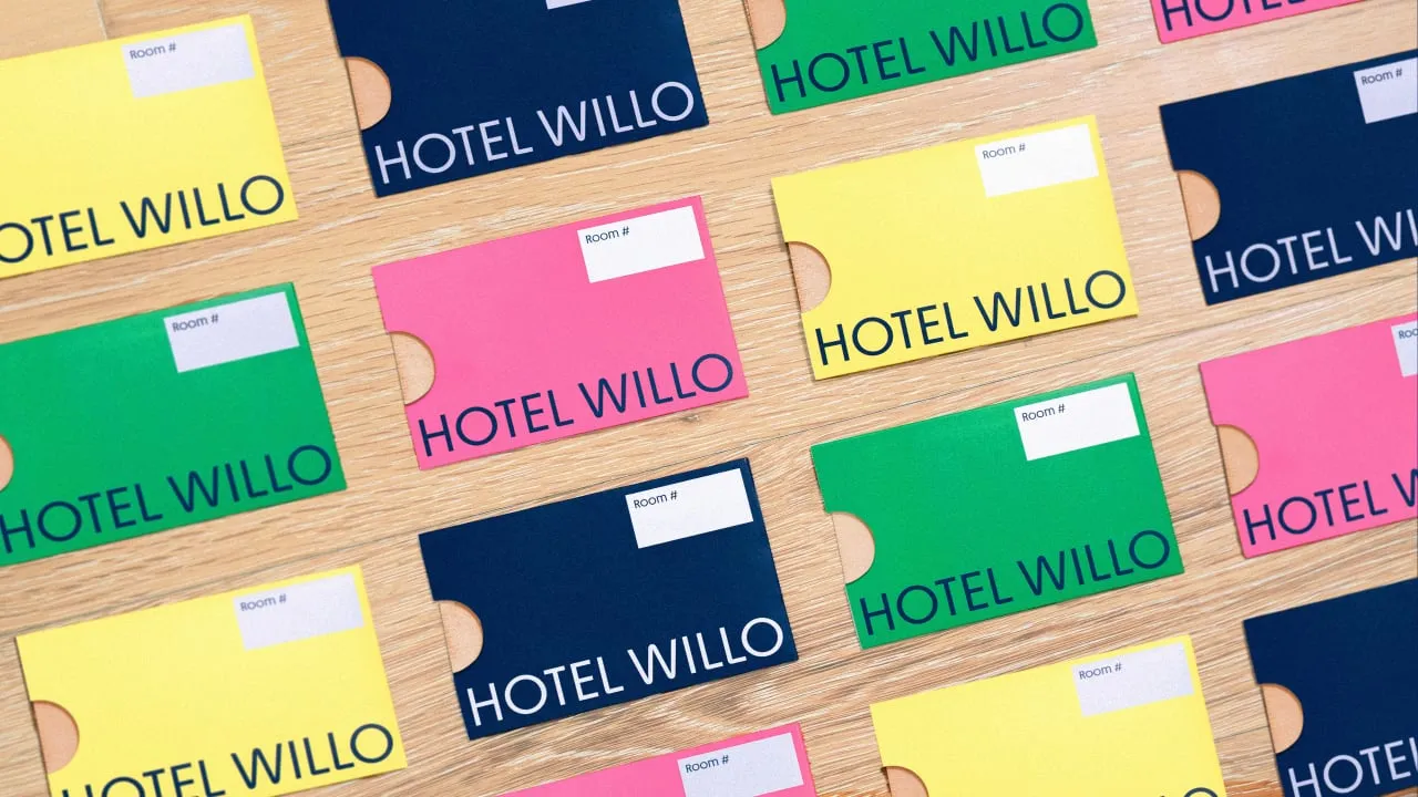 Tarjetas de llave de Hotel Willo en amarillo, verde, rosa y azul marino, dispuestas en diagonal sobre una mesa de madera
