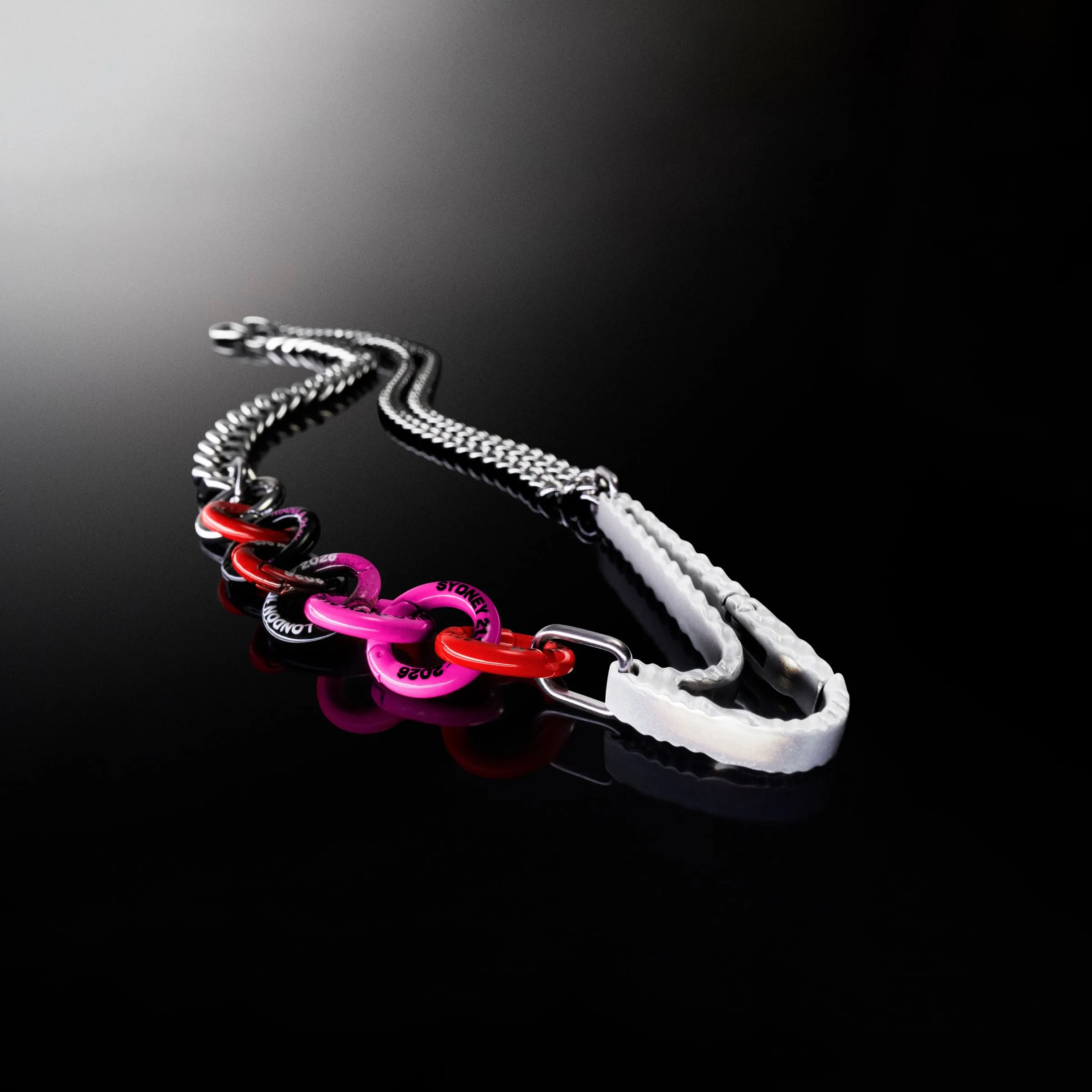 Cadena con una hilera de anillas rosas, rojas y negras junto al mosquetón blanco con forma de Swoosh