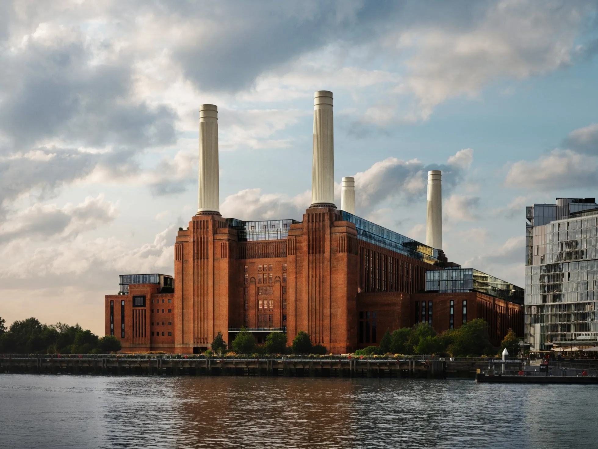 Fachada de ladrillo de la Battersea Power Station junto al Támesis, con sus cuatro chimeneas blancas recortadas contra el cielo