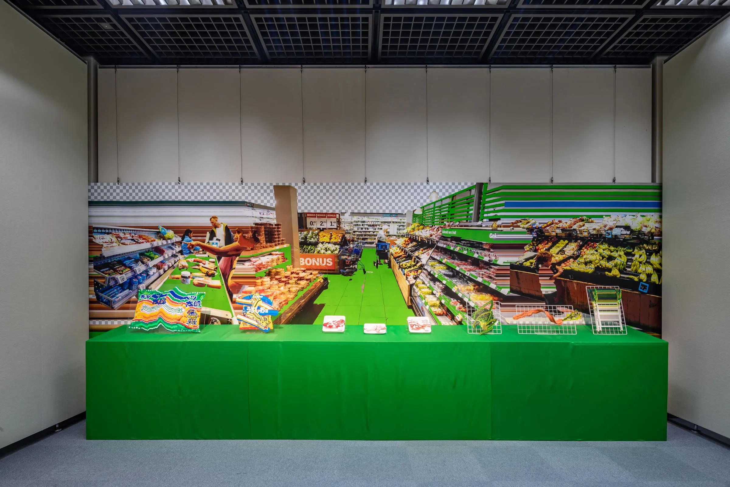 Instalación del supermercado: una gran imagen de pasillos con frutas y verduras detrás de una mesa verde con productos expuestos