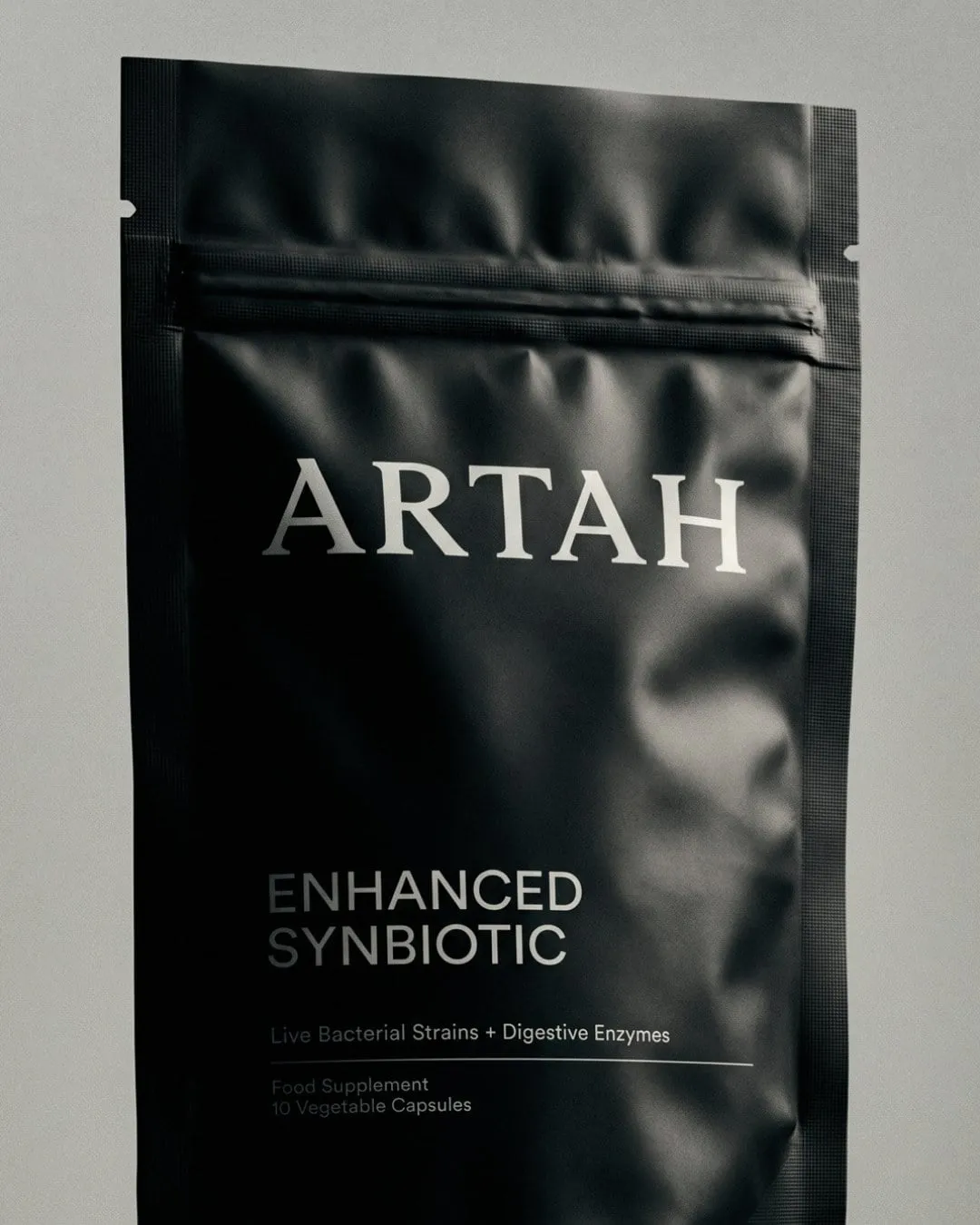 Bolsa negra mate de Artah con el nombre en letras plateadas y la etiqueta «Enhanced Synbiotic»