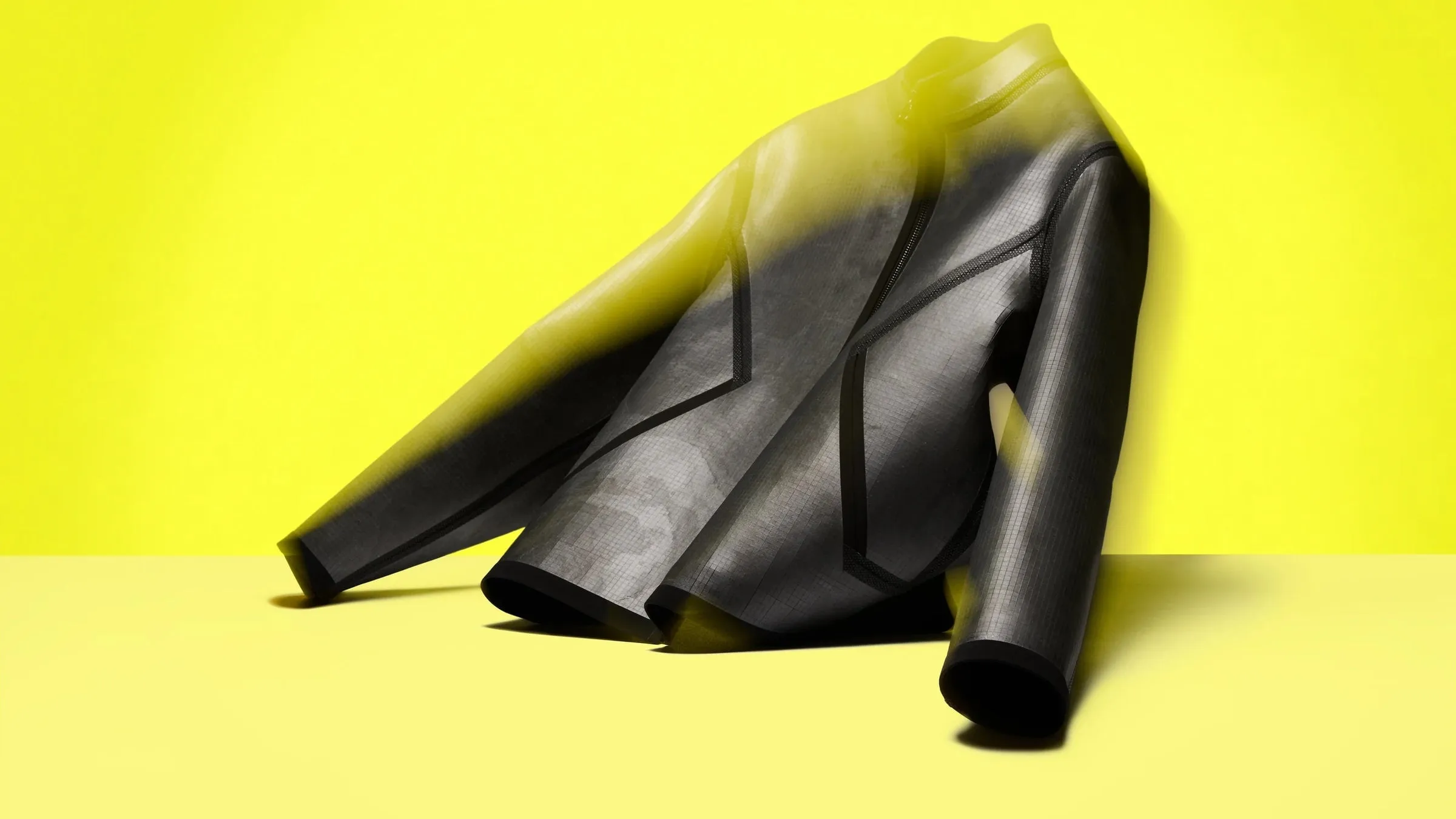 Chaqueta negra de pizarra vista de lado sobre fondo amarillo, con una mitad desenfocada como si estuviera en movimiento