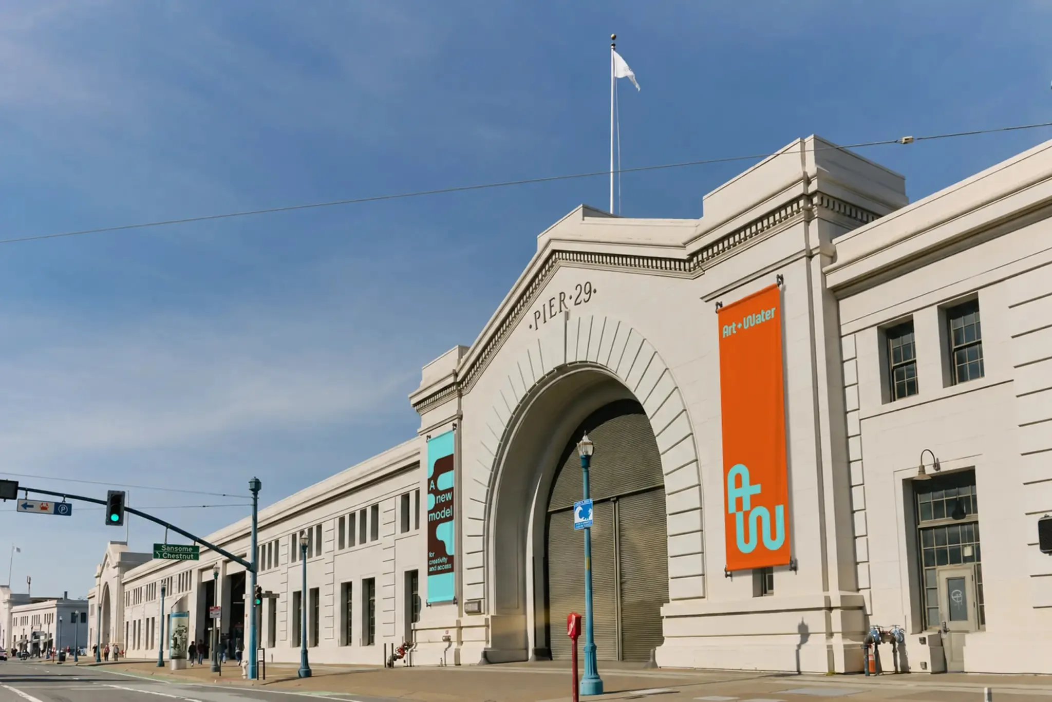 Fachada clásica del muelle 29 con un gran arco de entrada y banderolas naranja y turquesa con las siglas «AW»