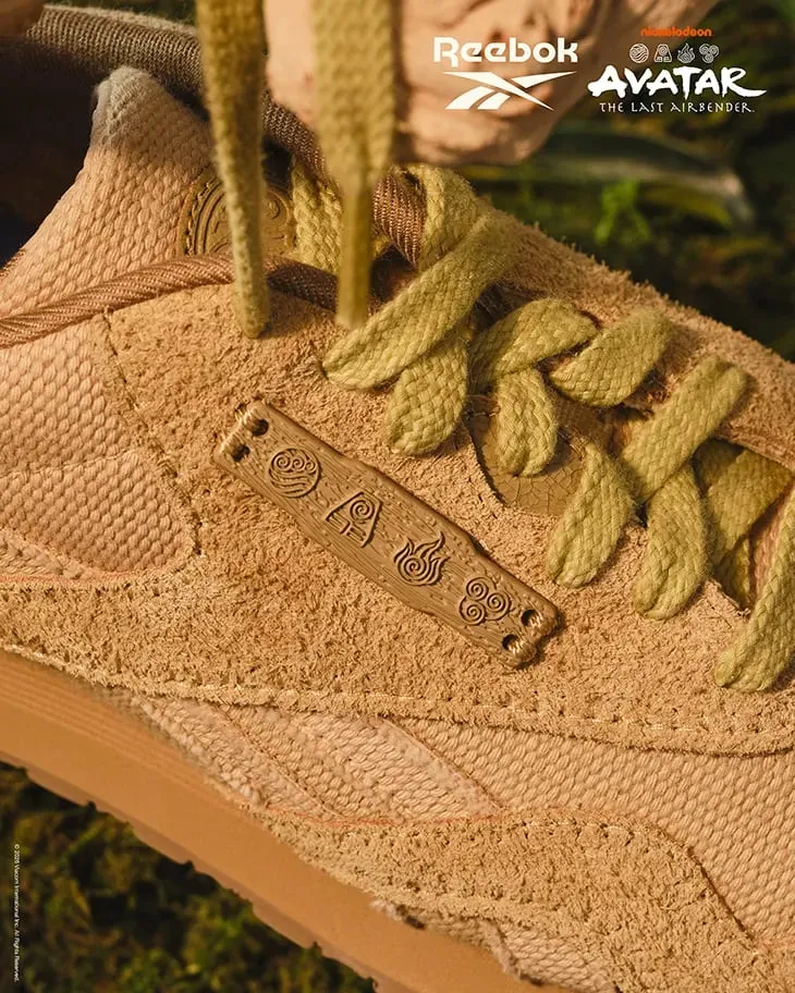 Detalle de la Classic Nylon en ante beige, con una placa metálica con los símbolos de los elementos y cordones de color verde