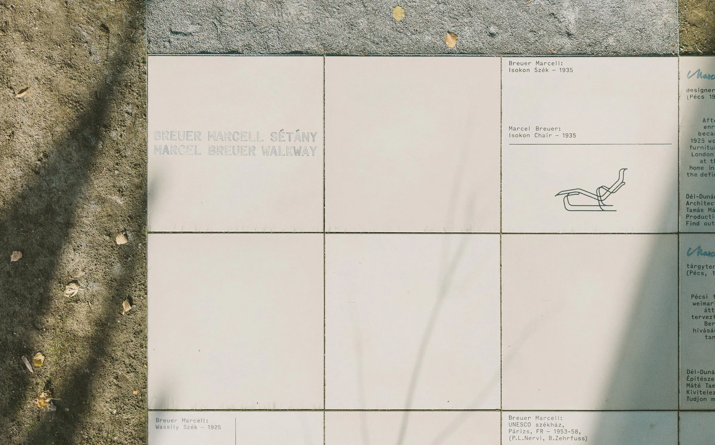Baldosas con el nombre del paseo, Breuer Marcell sétány, y el dibujo de la silla Isokon con su año