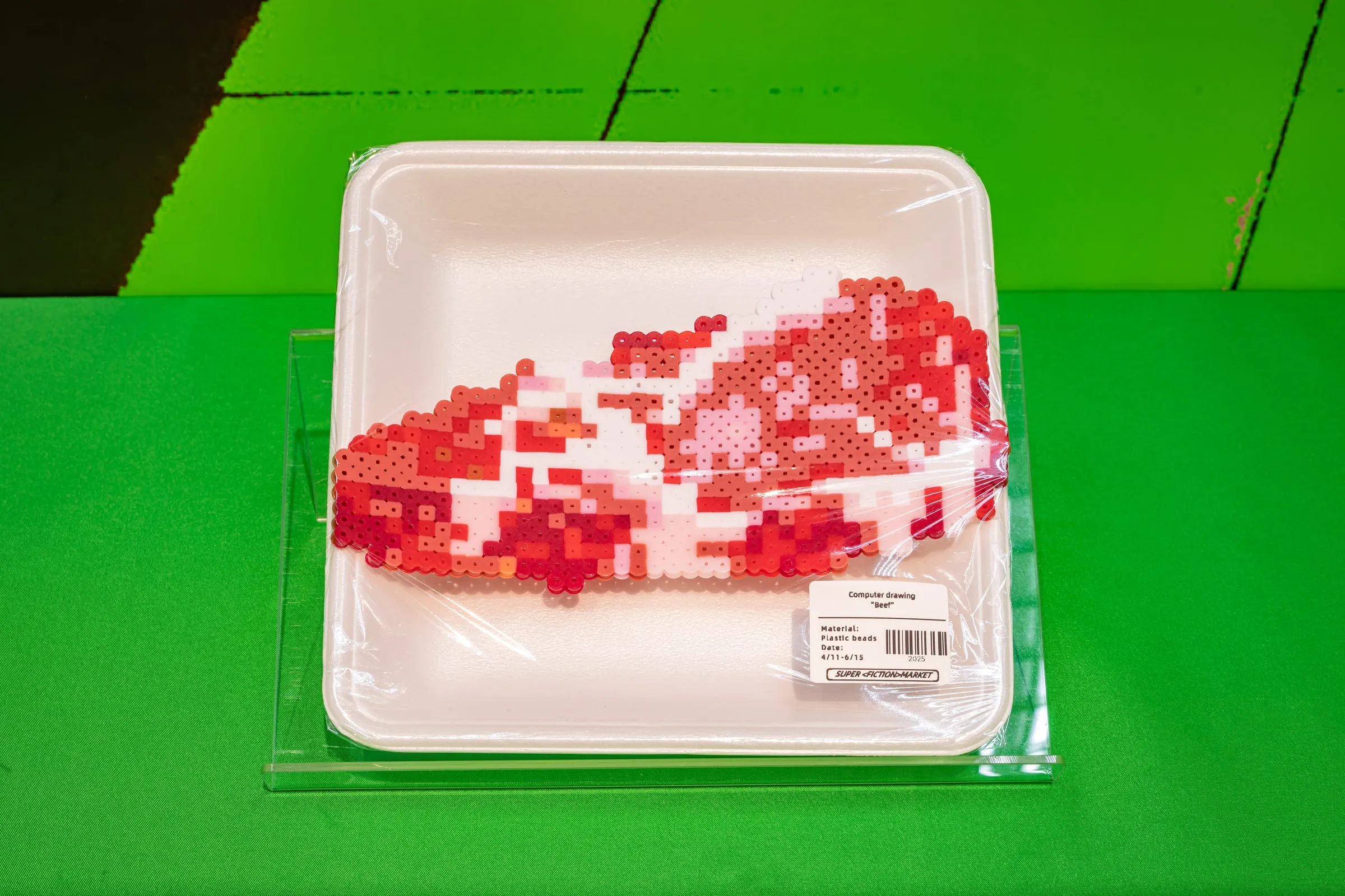 Bandeja de supermercado con un filete rojo y blanco hecho de cuentas de plástico, con su etiqueta de producto