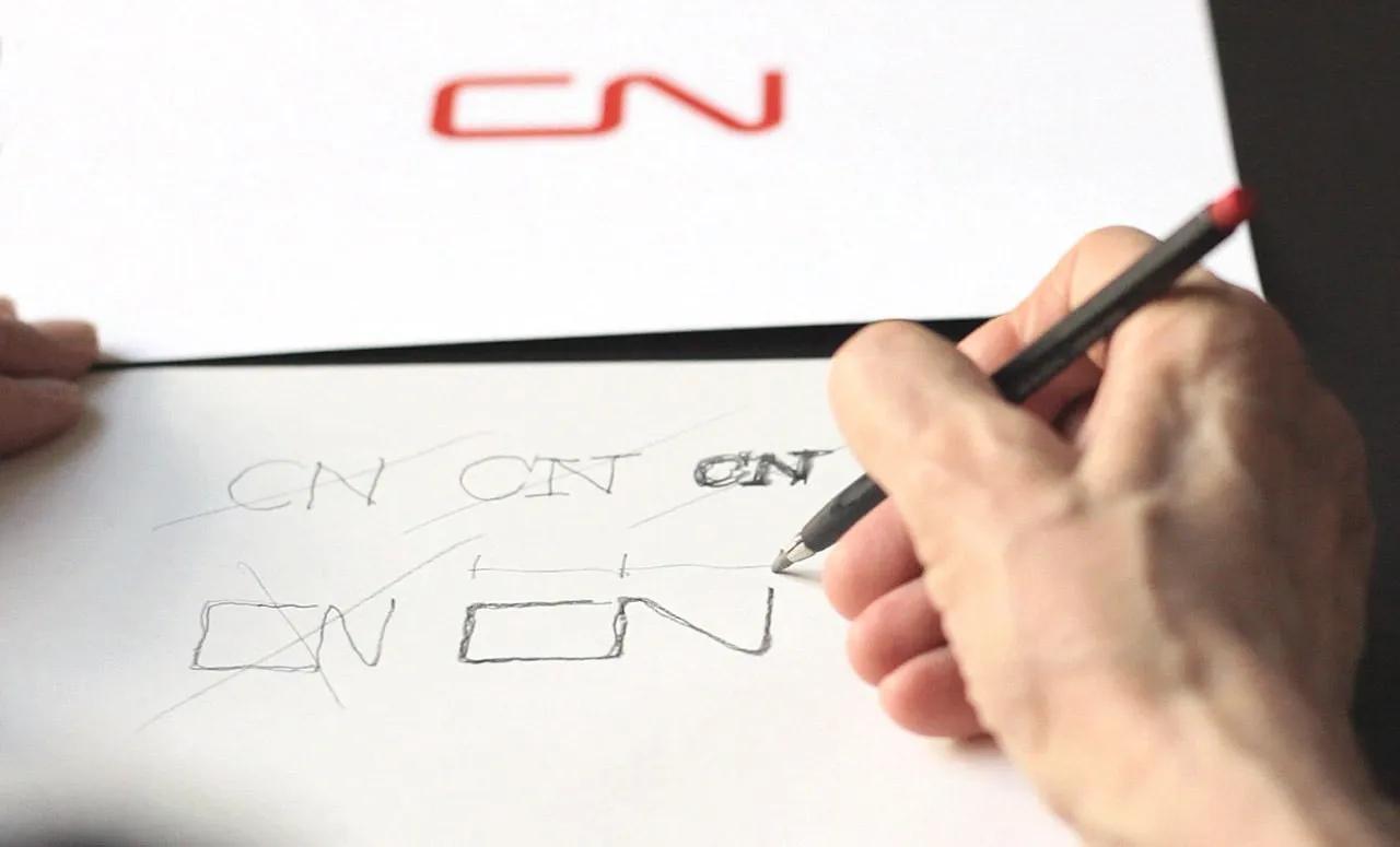 Una mano dibuja a lápiz bocetos del logotipo CN de los ferrocarriles de Canadá