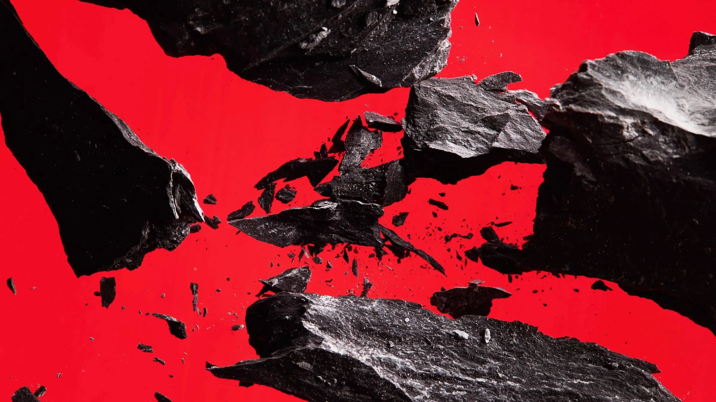 Fragmentos de pizarra negra rotos y astillados sobre un fondo rojo intenso