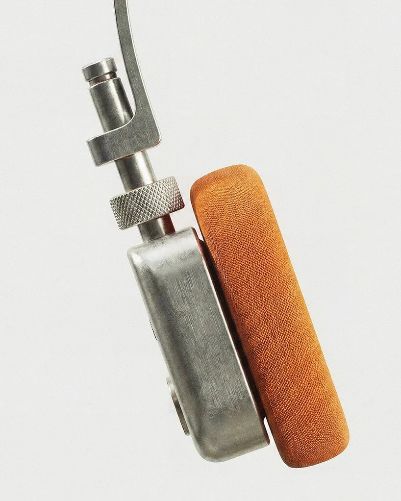 Vista lateral de un auricular: pieza cilíndrica con una rueda estriada, carcasa de aluminio y almohadilla de tela naranja