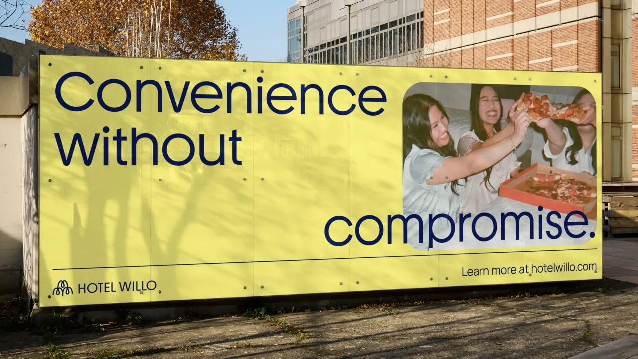 Valla publicitaria amarilla de Hotel Willo con el lema «Convenience without compromise» y una foto de amigas comiendo pizza
