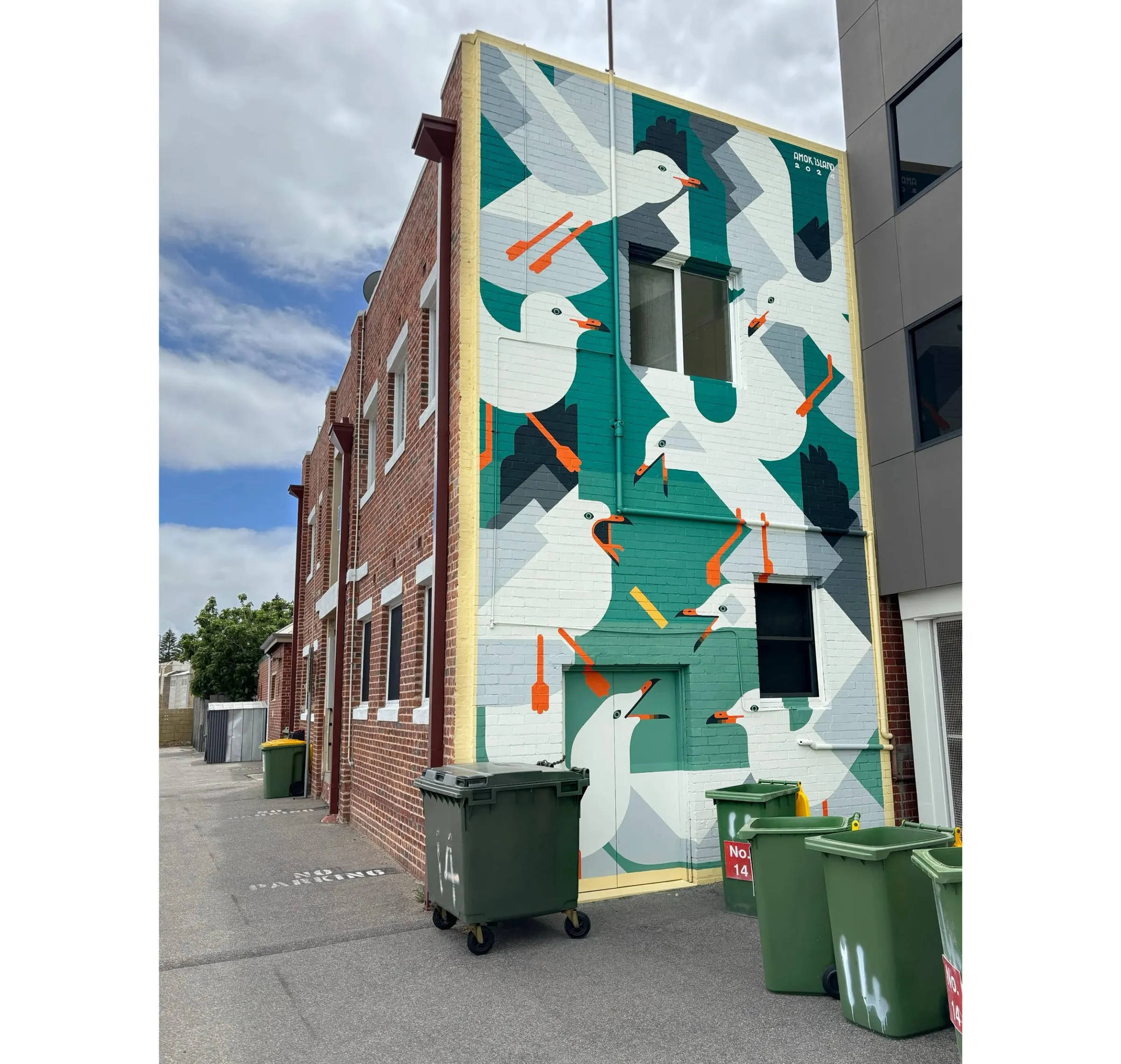 Gaviotas geométricas pintadas en una pared junto a contenedores de basura verdes
