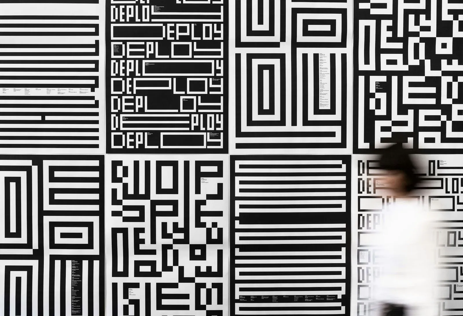 Pared de carteles cuadrados en blanco y negro con la palabra Deploy en letras geométricas hechas de barras