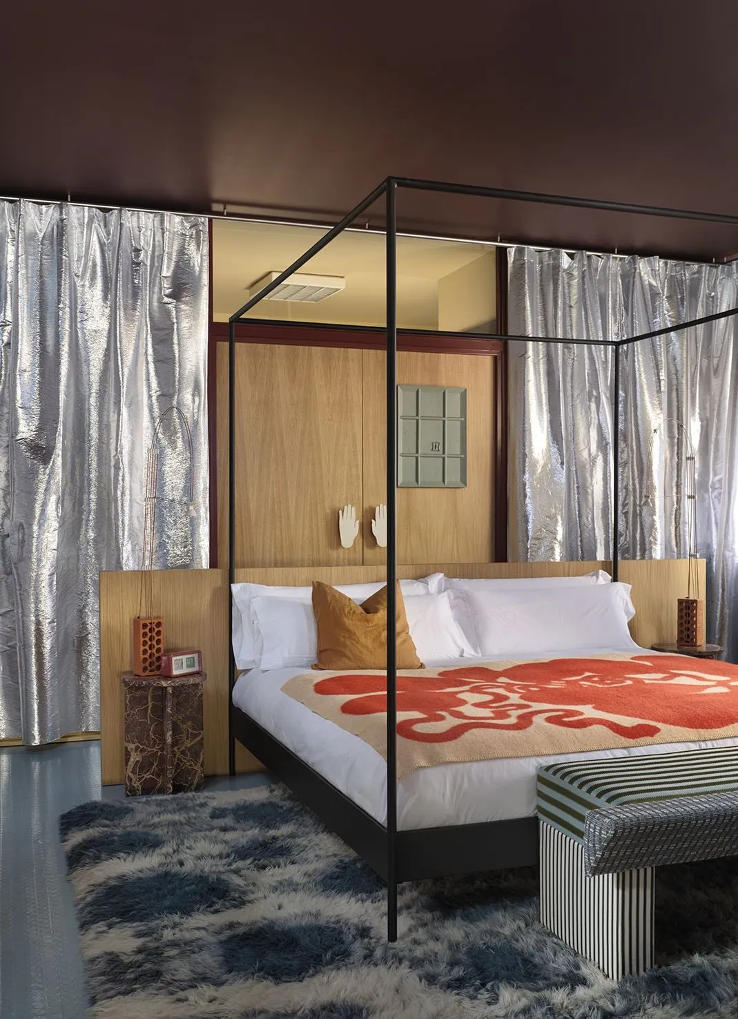 Dormitorio con cama de dosel tubular negro, techo granate mate y cortina de tela plateada