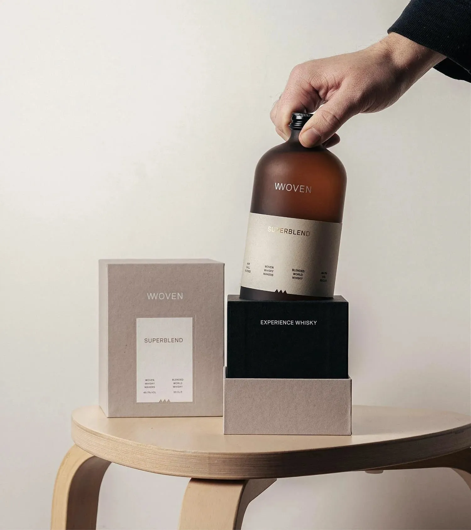 Una mano saca de una caja una botella de Superblend, junto a otra caja gris y un cajetín negro