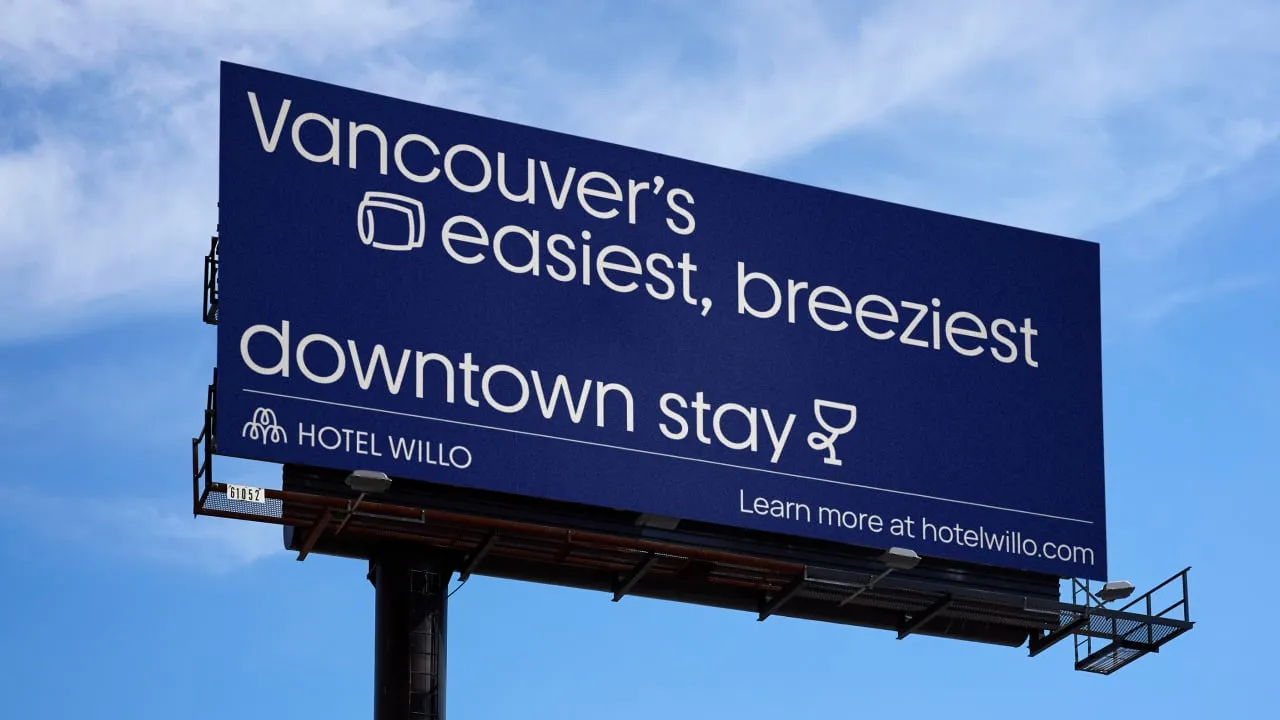 Valla publicitaria azul marino de Hotel Willo con el lema «Vancouver's easiest, breeziest downtown stay» contra un cielo despejado