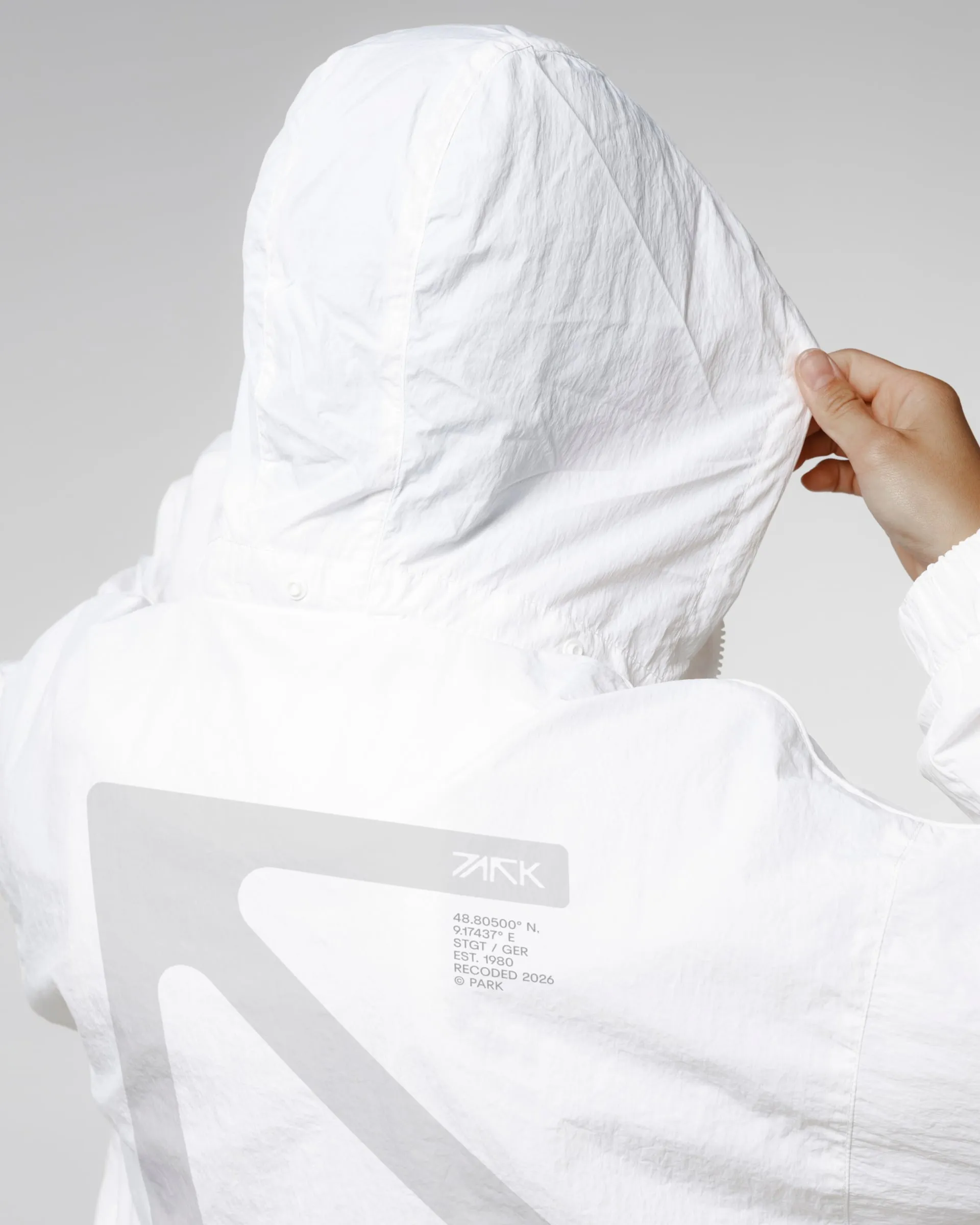 Espalda de una sudadera blanca con el logotipo de PARK impreso en gris junto a las coordenadas del club en Stuttgart
