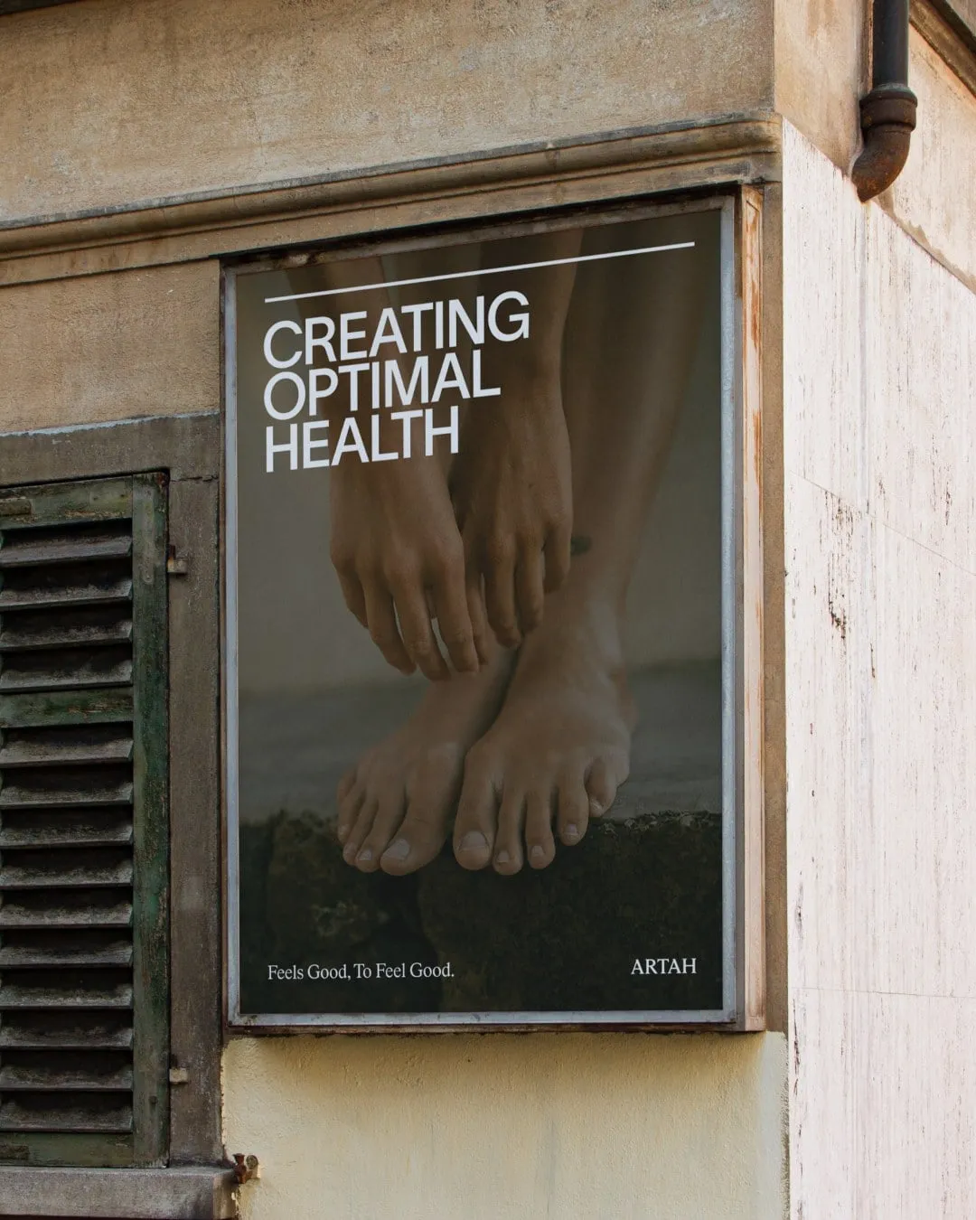 Cartel de Artah colgado en la esquina de un edificio de piedra, con unos pies descalzos y el texto «Creating optimal health»