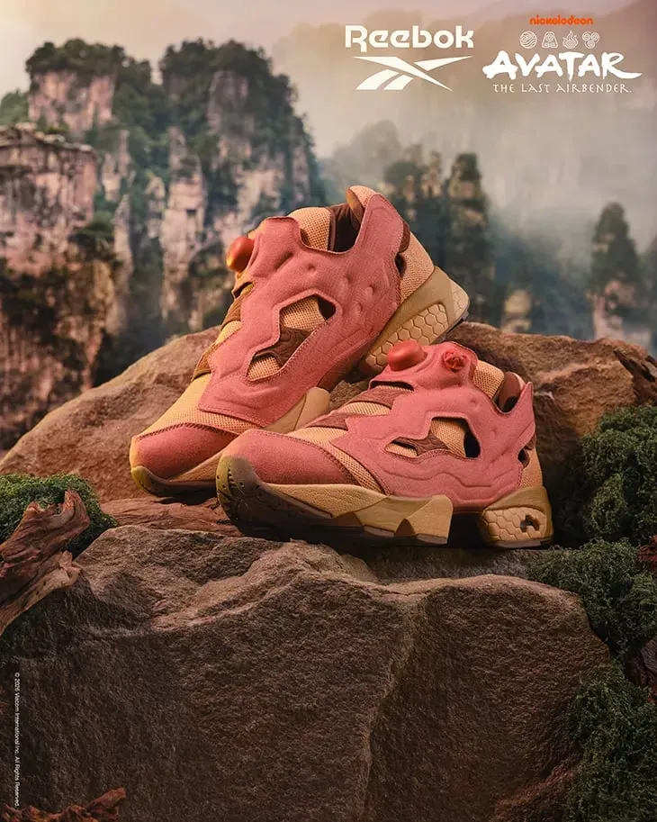 Un par de Insta Pump Fury 94 en tonos salmón y arena sobre una roca, con montañas verdes de fondo
