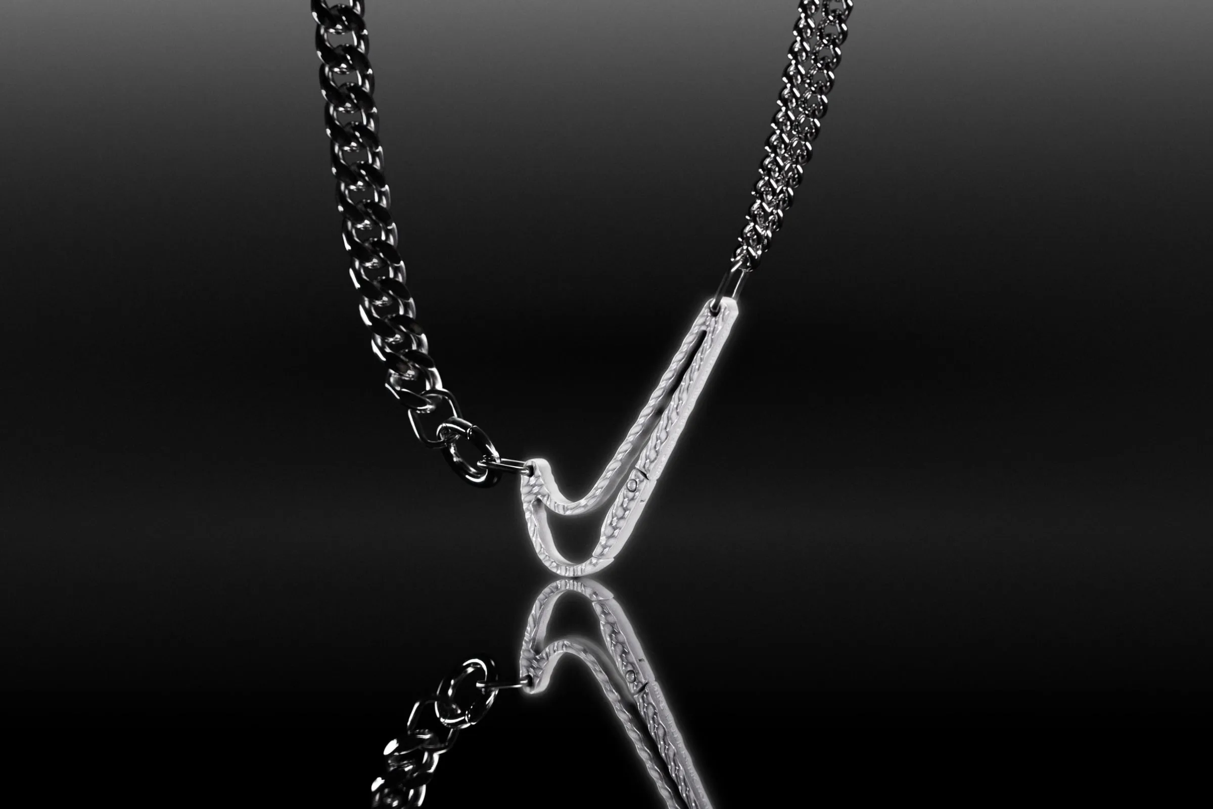 Cadena plateada y oscura con el Swoosh de relieve fino colgando como cierre, vista desde arriba