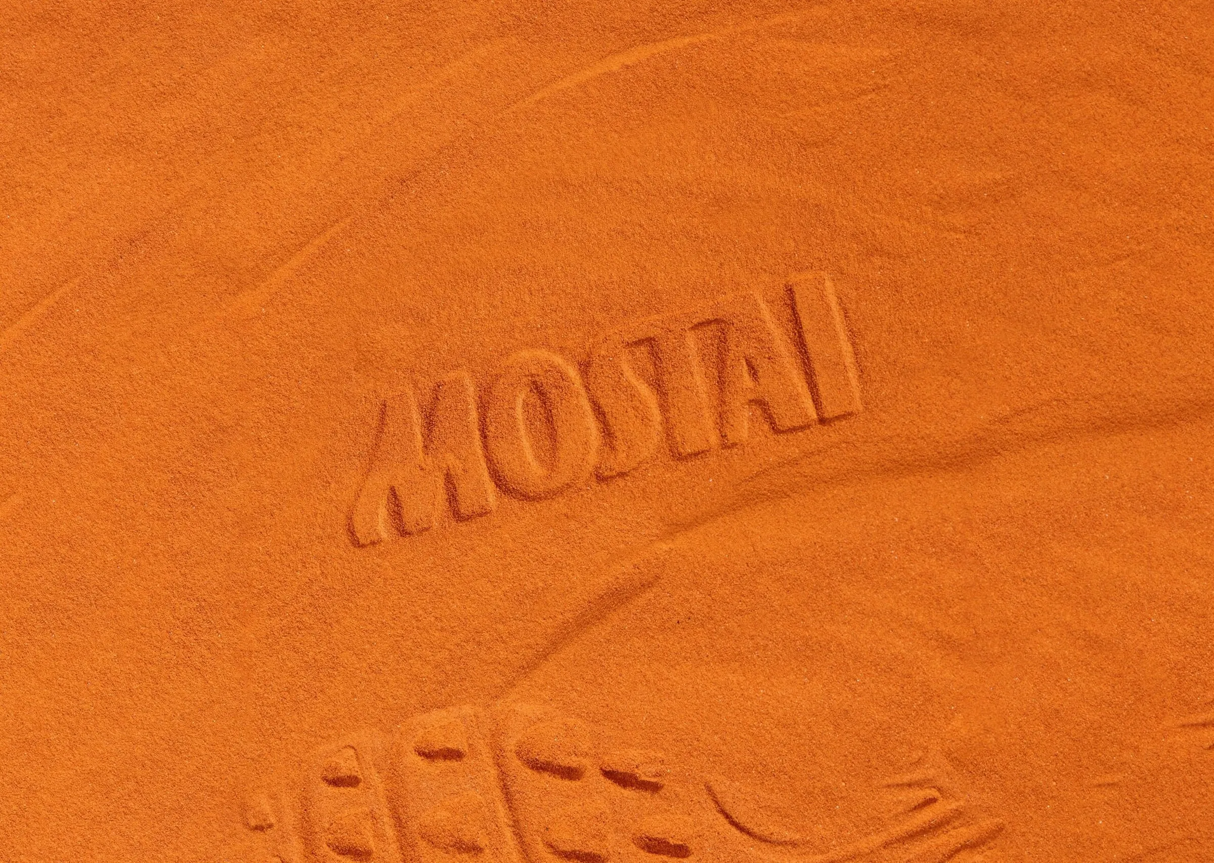 Nombre de Mostai grabado en relieve sobre arena anaranjada