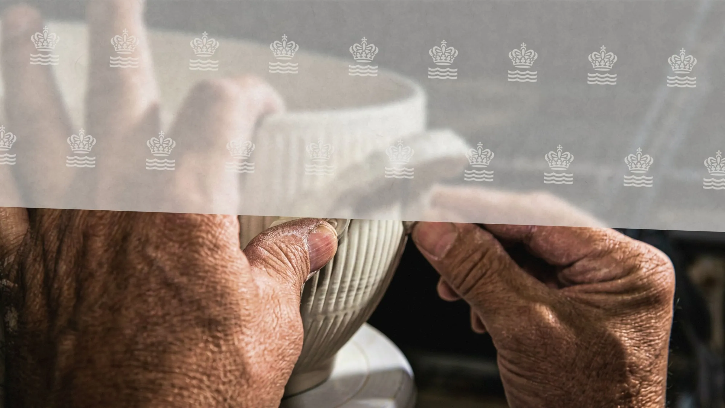 Primer plano de unas manos curtidas sujetando una taza de porcelana acanalada, con una banda translúcida de coronas y olas encima