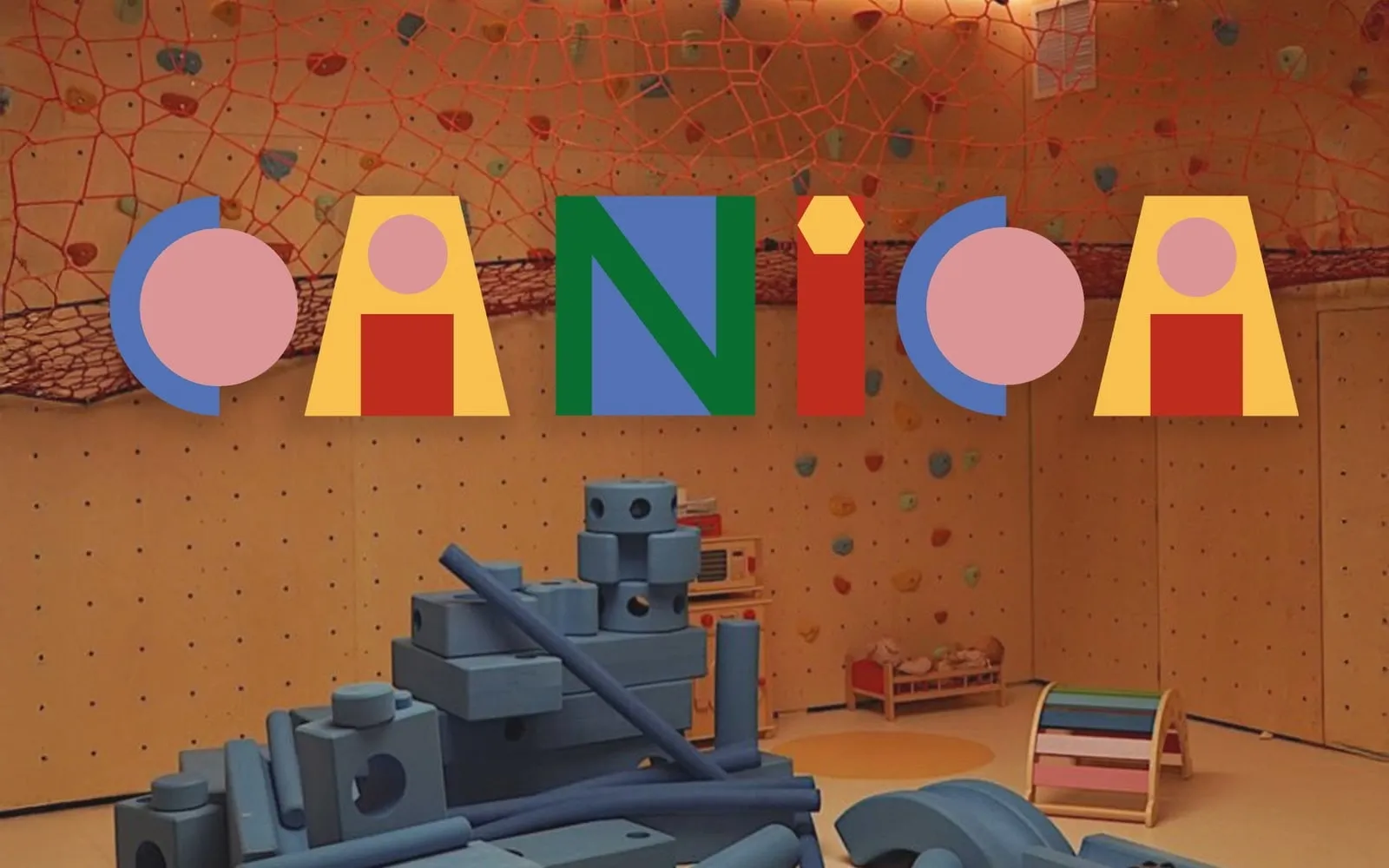 Logotipo de Canica formado por círculos, trapecios y rectángulos de colores sobre una sala de juegos con red roja y bloques azules