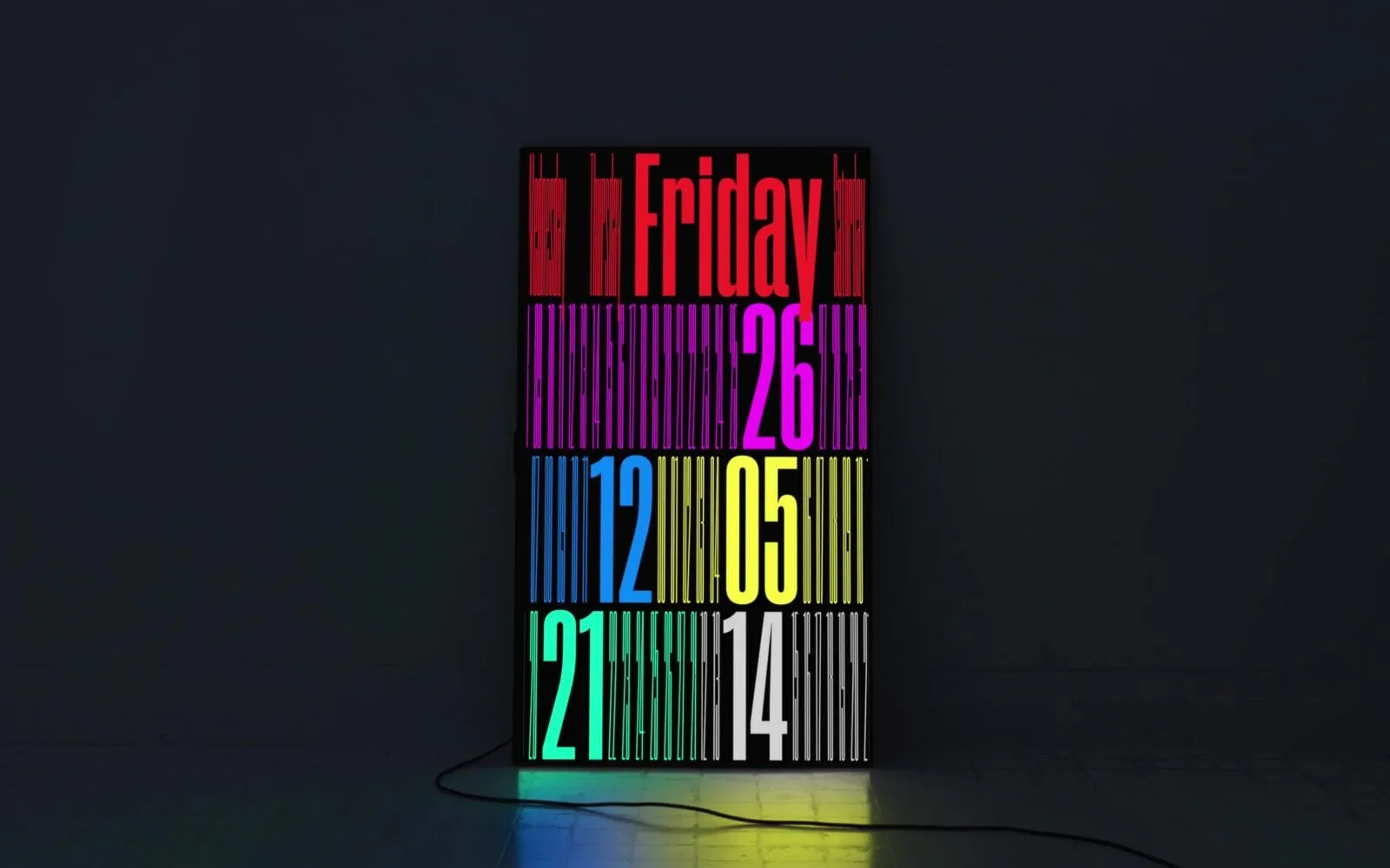 Pantalla vertical en una sala oscura con un reloj tipográfico: «Friday», 26, 12, 05, 21 y 14 en letras muy estrechas de colores sobre fondo negro