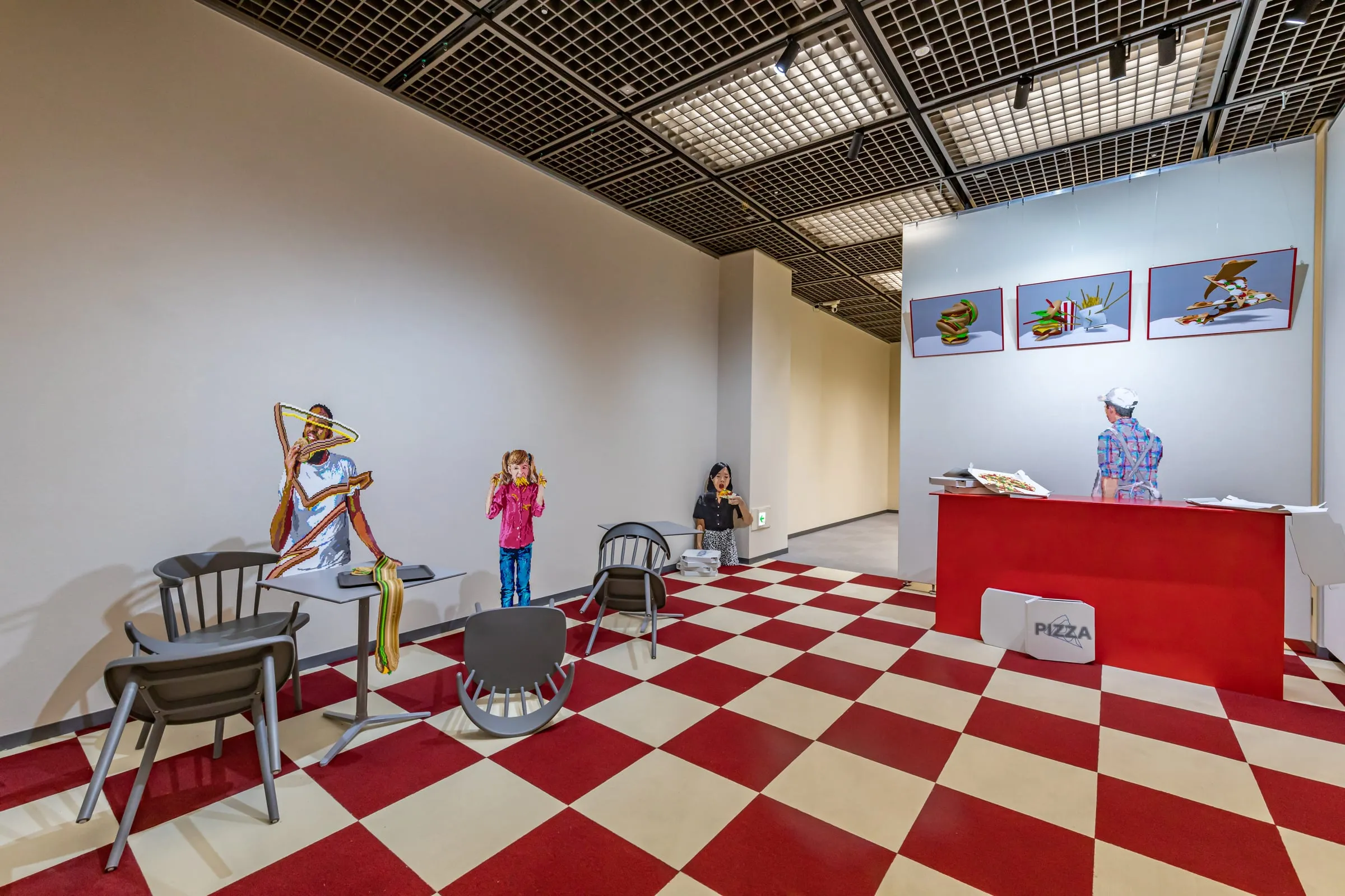 Sala con suelo de cuadros rojos y blancos y un mostrador rojo de pizzería, con figuras pixeladas de personas comiendo y sillas volcadas